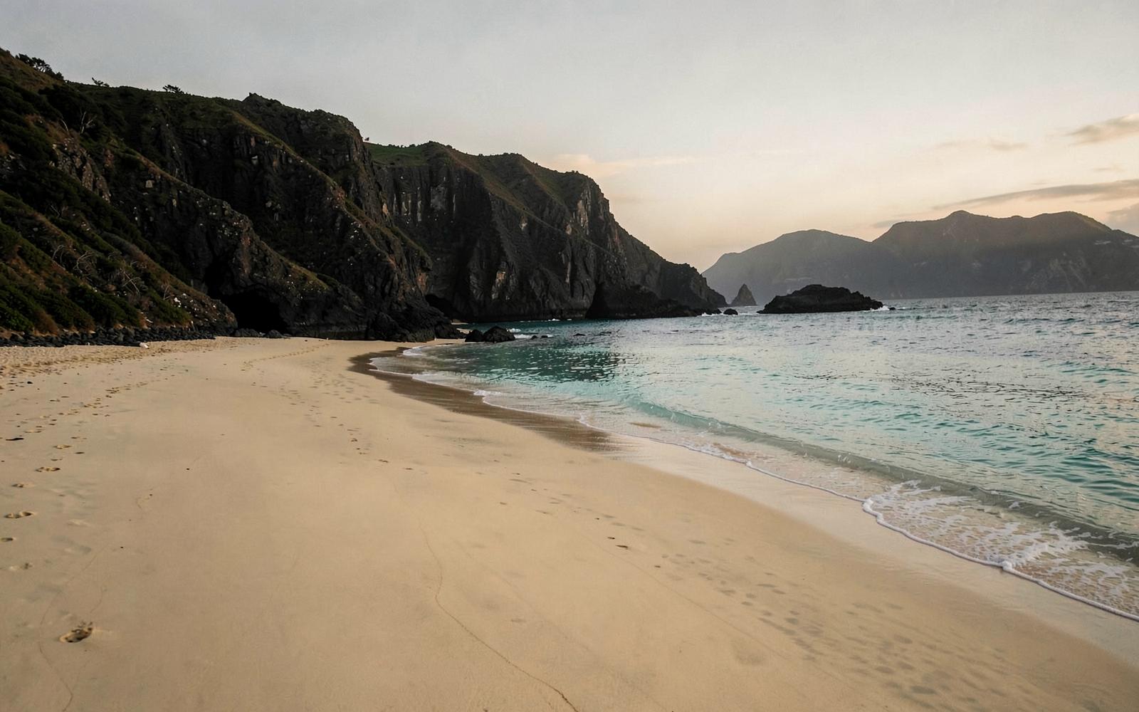 Golden sand bay with turquoise water and dark cliffs